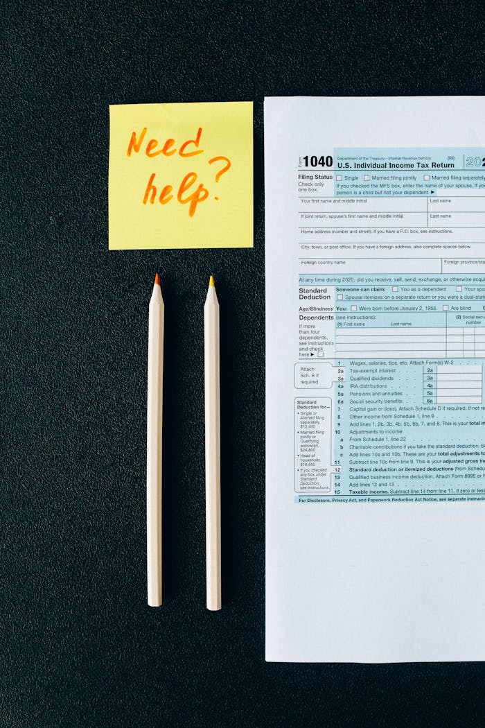 heros-img A tax form 1040 with a 'Need help?' sticky note and pencils on a black surface.